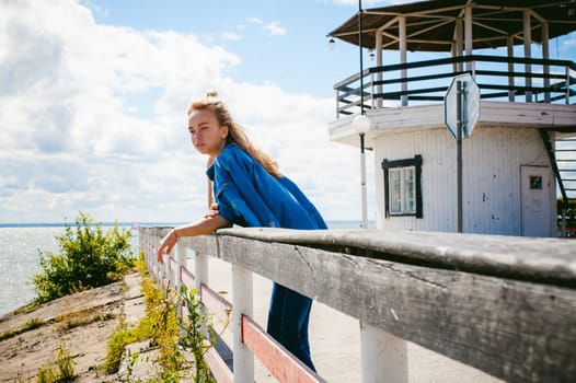 young beautiful woman in jeans clothes outdoors. portrait of a girl with freckles on her face, stylish girl on sea beach, on a sunny summer autumn day.