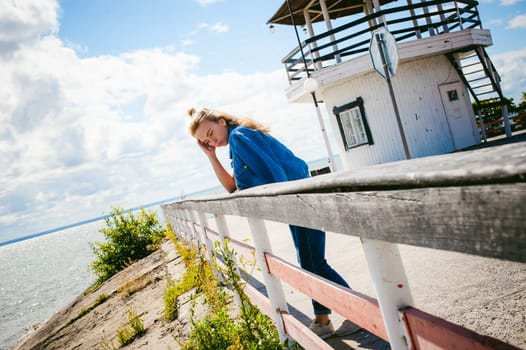 young beautiful woman in jeans clothes outdoors. portrait of a girl with freckles on her face, stylish girl on sea beach, on a sunny summer autumn day.