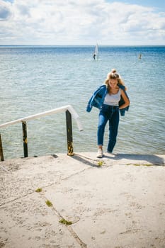 young beautiful woman in jeans clothes outdoors. portrait of a girl with freckles on her face, stylish girl on sea beach, on a sunny summer autumn day.