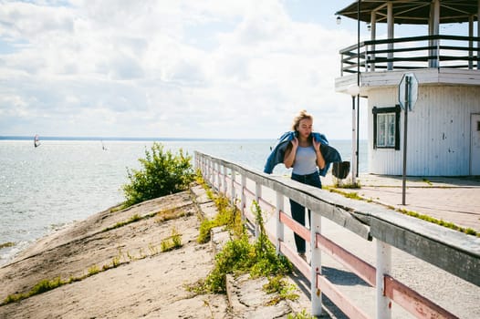 young beautiful woman in jeans clothes outdoors. portrait of a girl with freckles on her face, stylish girl on sea beach, on a sunny summer autumn day.