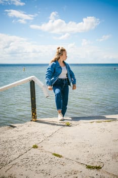 young beautiful woman in jeans clothes outdoors. portrait of a girl with freckles on her face, stylish girl on sea beach, on a sunny summer autumn day.