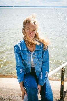 young beautiful woman in jeans clothes outdoors. portrait of a girl with freckles on her face, stylish girl on sea beach, on a sunny summer autumn day.