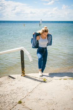 young beautiful woman in jeans clothes outdoors. portrait of a girl with freckles on her face, stylish girl on sea beach, on a sunny summer autumn day.