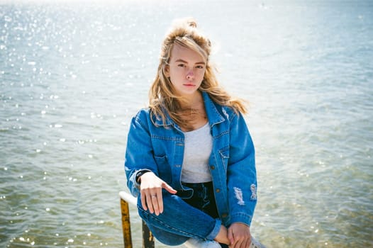 young beautiful woman in jeans clothes outdoors. portrait of a girl with freckles on her face, stylish girl on sea beach, on a sunny summer autumn day.