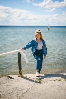 young beautiful woman in jeans clothes outdoors. portrait of a girl with freckles on her face, stylish girl on sea beach, on a sunny summer autumn day.