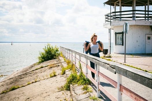 young beautiful woman in jeans clothes outdoors. portrait of a girl with freckles on her face, stylish girl on sea beach, on a sunny summer autumn day.