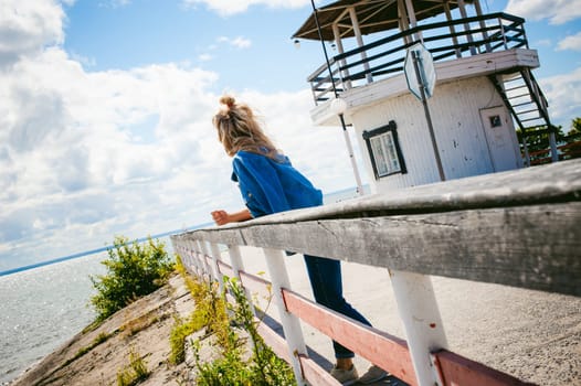young beautiful woman in jeans clothes outdoors. portrait of a girl with freckles on her face, stylish girl on sea beach, on a sunny summer autumn day.