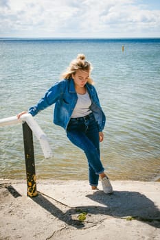 young beautiful woman in jeans clothes outdoors. portrait of a girl with freckles on her face, stylish girl on sea beach, on a sunny summer autumn day.