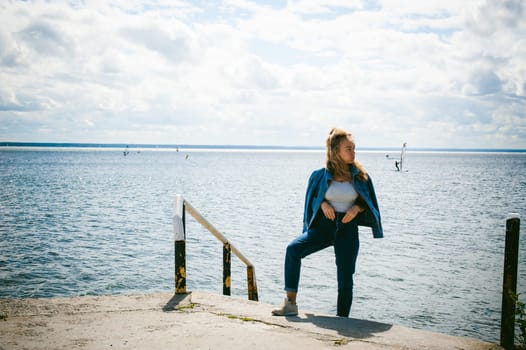 young beautiful woman in jeans clothes outdoors. portrait of a girl with freckles on her face, stylish girl on sea beach, on a sunny summer autumn day.