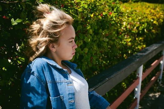 young beautiful woman in jeans clothes outdoors. portrait of a girl with freckles on her face, stylish girl on a sunny summer autumn day.