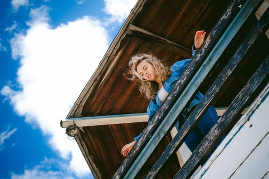 young beautiful woman in jeans clothes outdoors. portrait of a girl with freckles on her face, stylish girl on sea beach rescue tower, on a sunny summer autumn day.