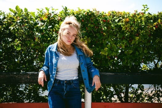 young beautiful woman in jeans clothes outdoors. portrait of a girl with freckles on her face, stylish girl on a sunny summer autumn day.