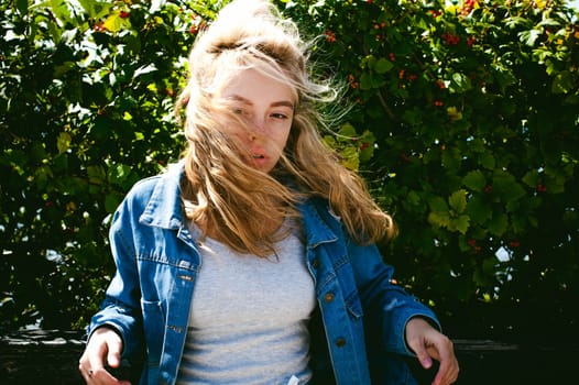 young beautiful woman in jeans clothes outdoors. portrait of a girl with freckles on her face, stylish girl on a sunny summer autumn day.