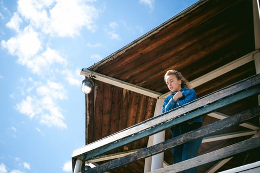 young beautiful woman in jeans clothes outdoors. portrait of a girl with freckles on her face, stylish girl on sea beach rescue tower, on a sunny summer autumn day.