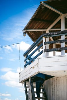 young beautiful woman in jeans clothes outdoors. portrait of a girl with freckles on her face, stylish girl on sea beach rescue tower, on a sunny summer autumn day.