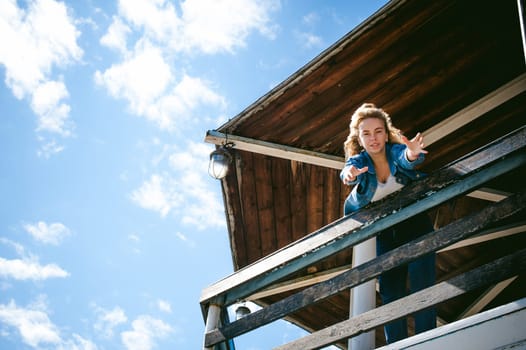 young beautiful woman in jeans clothes outdoors. portrait of a girl with freckles on her face, stylish girl on sea beach rescue tower, on a sunny summer autumn day. happy pulls hands to hug