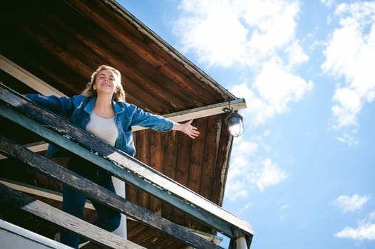 young beautiful woman in jeans clothes outdoors. portrait of a girl with freckles on her face, stylish girl on sea beach rescue tower, on a sunny summer autumn day. happy pulls hands to hug