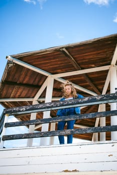 young beautiful woman in jeans clothes outdoors. portrait of a girl with freckles on her face, stylish girl on sea beach rescue tower, on a sunny summer autumn day.
