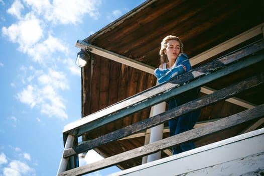 young beautiful woman in jeans clothes outdoors. portrait of a girl with freckles on her face, stylish girl on sea beach rescue tower, on a sunny summer autumn day.