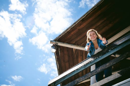young beautiful woman in jeans clothes outdoors. portrait of a girl with freckles on her face, stylish girl on sea beach rescue tower, on a sunny summer autumn day. happy pulls hands to hug