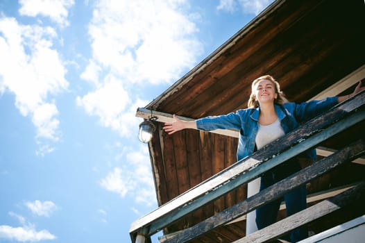 young beautiful woman in jeans clothes outdoors. portrait of a girl with freckles on her face, stylish girl on sea beach rescue tower, on a sunny summer autumn day. happy pulls hands to hug