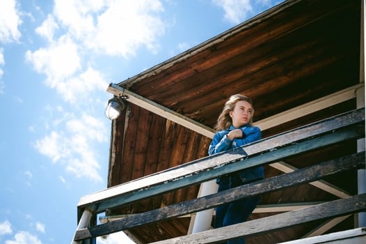 young beautiful woman in jeans clothes outdoors. portrait of a girl with freckles on her face, stylish girl on sea beach rescue tower, on a sunny summer autumn day.