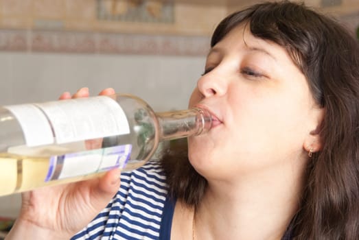 Girl drinking wine from the neck of a glass bottle.