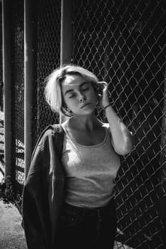 young woman in jeans clothes outdoors. portrait of a girl with freckles on her face, stylish girl on a fence of a grid, a sunny summer day...