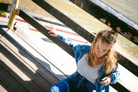 young beautiful woman in jeans clothes outdoors. portrait of a girl with freckles on her face, stylish girl on sea beach rescue tower, on a sunny summer autumn day.