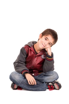 Beautiful young boy seated on the floor isolated in white