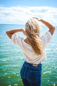 Portrait young woman on stones near sea. Beautiful girl is resting on coast, enjoying outdoor recreation.