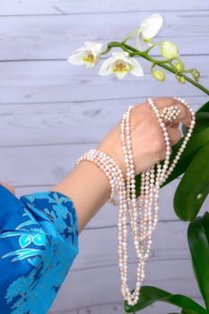 Woman cares for white orchid, wearing ring of Japanese white pearls.