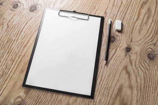 Clipboard with blank letterhead, pencil and eraser on wooden table background. Blank stationery template with plenty of copy space.