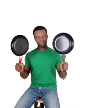 A would be cook sitting in a green polo shirt holding up two empty.freeing pan's looking puzzled, isolated for white background.