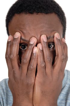 A young African American man in a close up image holding his hands.over his face, looking trough, isolated for white background.