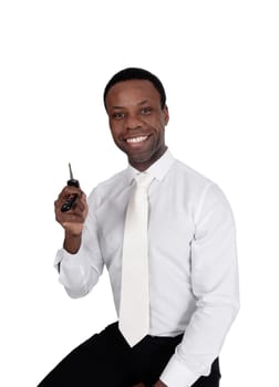 A young handsome African American man sitting in a white shirt and.tie holding up his new car key's, isolated for white background.