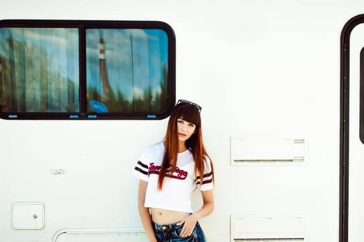 portrait attractive women in sports white T-shirt against background of Camper Trailer, transport for travel