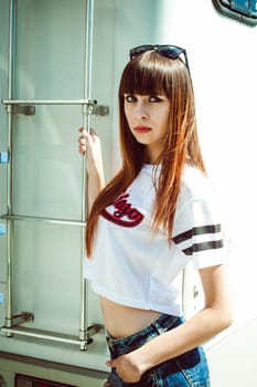 portrait attractive women in sports white T-shirt against background of Camper Trailer, transport for travel