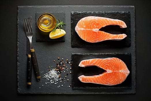 Slice of red fish salmon with lemon and rosemary on black background.