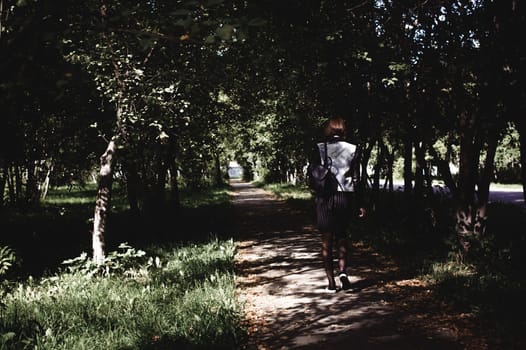 street portrait of a girl student, fashionably dressed in dark clothes, with a black backpack and denim jacket autumn sunny day