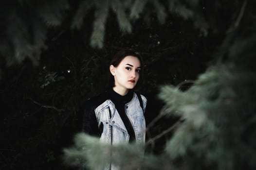 street portrait of a girl student, fashionably dressed in dark clothes, with a black backpack and denim jacket autumn sunny day