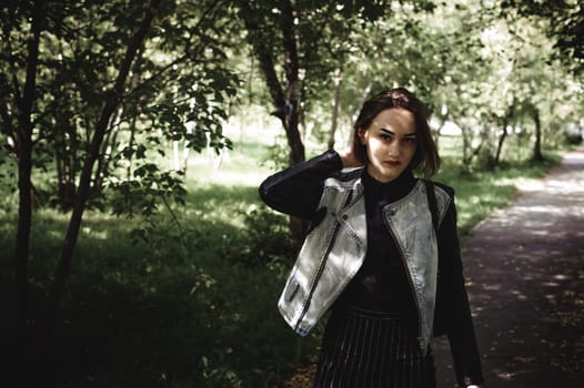 street portrait of a girl student, fashionably dressed in dark clothes, with a black backpack and denim jacket autumn sunny day