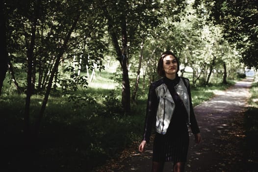 street portrait of a girl student, fashionably dressed in dark clothes, with a black backpack and denim jacket autumn sunny day
