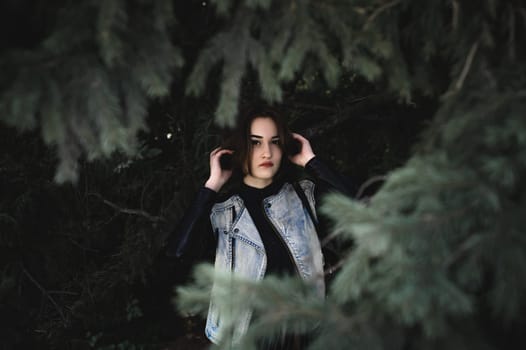 street portrait of a girl student, fashionably dressed in dark clothes, with a black backpack and denim jacket autumn sunny day
