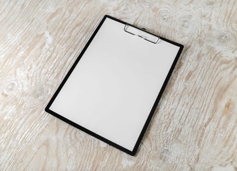 Clipboard with blank letterhead on wood table background. Stationery mockup with plenty of copy space.