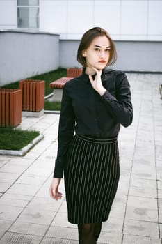 street portrait of a student girl dressed fashionably in dark clothes, on an autumn sunny day