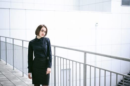 street portrait of a student girl dressed fashionably in dark clothes, on an autumn sunny day