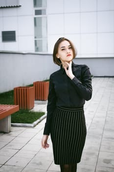 street portrait of a student girl dressed fashionably in dark clothes, on an autumn sunny day
