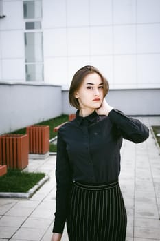 street portrait of a student girl dressed fashionably in dark clothes, on an autumn sunny day
