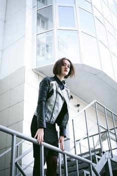 street portrait of a girl student, fashionably dressed in dark clothes, with a black backpack and denim jacket autumn sunny day